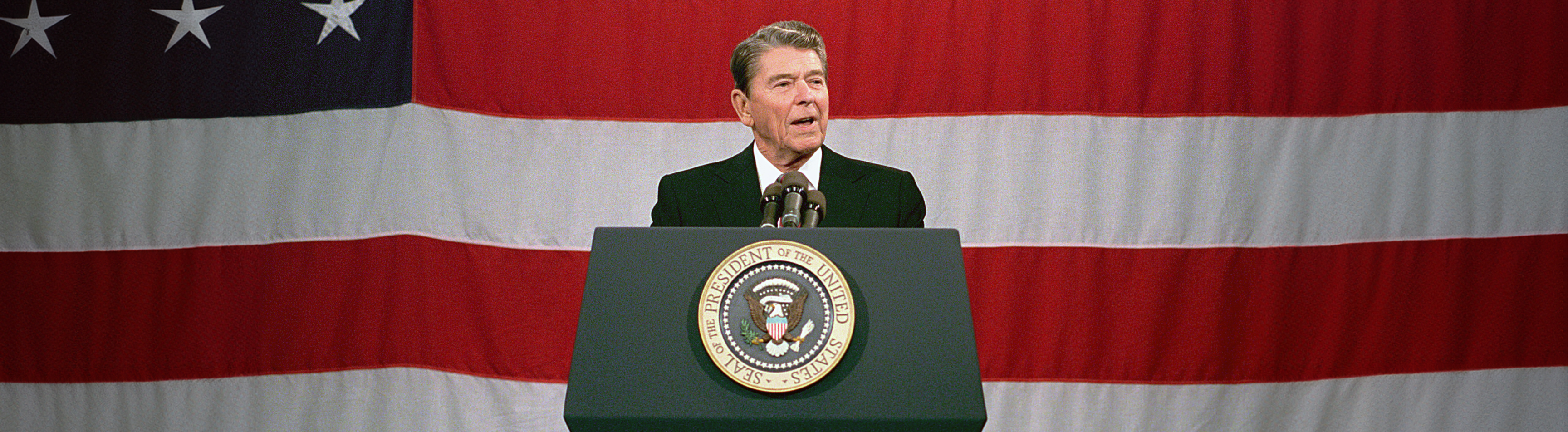 Ronald Reagan giving a speech in front of the American Flag