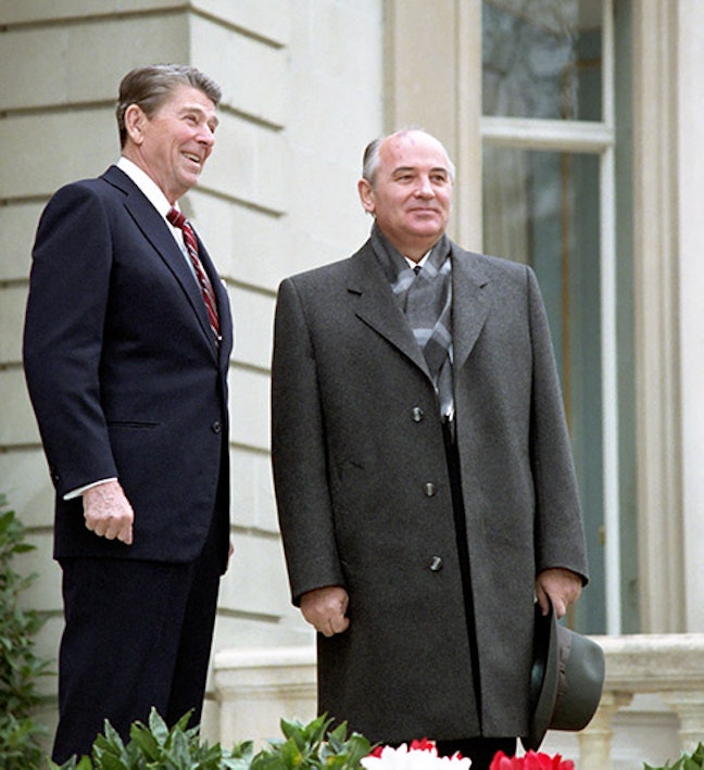 President Reagan's first meeting with Soviet General Secretary Gorbachev at Fleur D'Eau during the Geneva Summit in Switzerland . 11/19/1985. Two men stand smiling outside of a stone building overlooking a garden