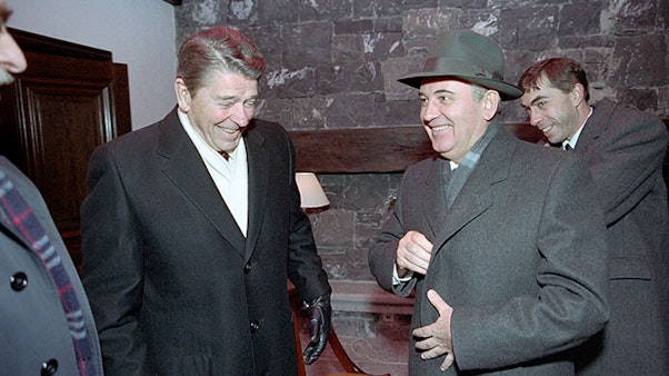 President Reagan and Soviet General Secretary Gorbachev leaving their meeting in the boathouse during the Geneva Summit in Switzerland. 11/19/1985. Two men in jackets laugh outside of a stone building
