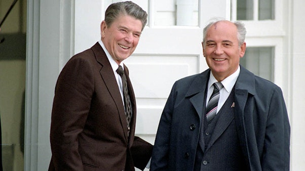 President Reagan and Soviet General Secretary Gorbachev at the Hofdi House in Reykjavik, Iceland during the Reyjavik Summit. 10/11/1986. Two men smiling in suits and jackets outside of a white building
