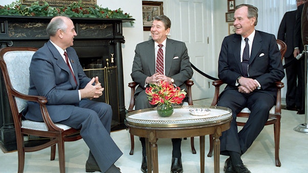 President Reagan, Vice-President Bush meet with Soviet General Secretary Gorbachev at Quarters One on Governor's Island, New York. 12/07/1988. Three men sit at a coffee table smiling and talking