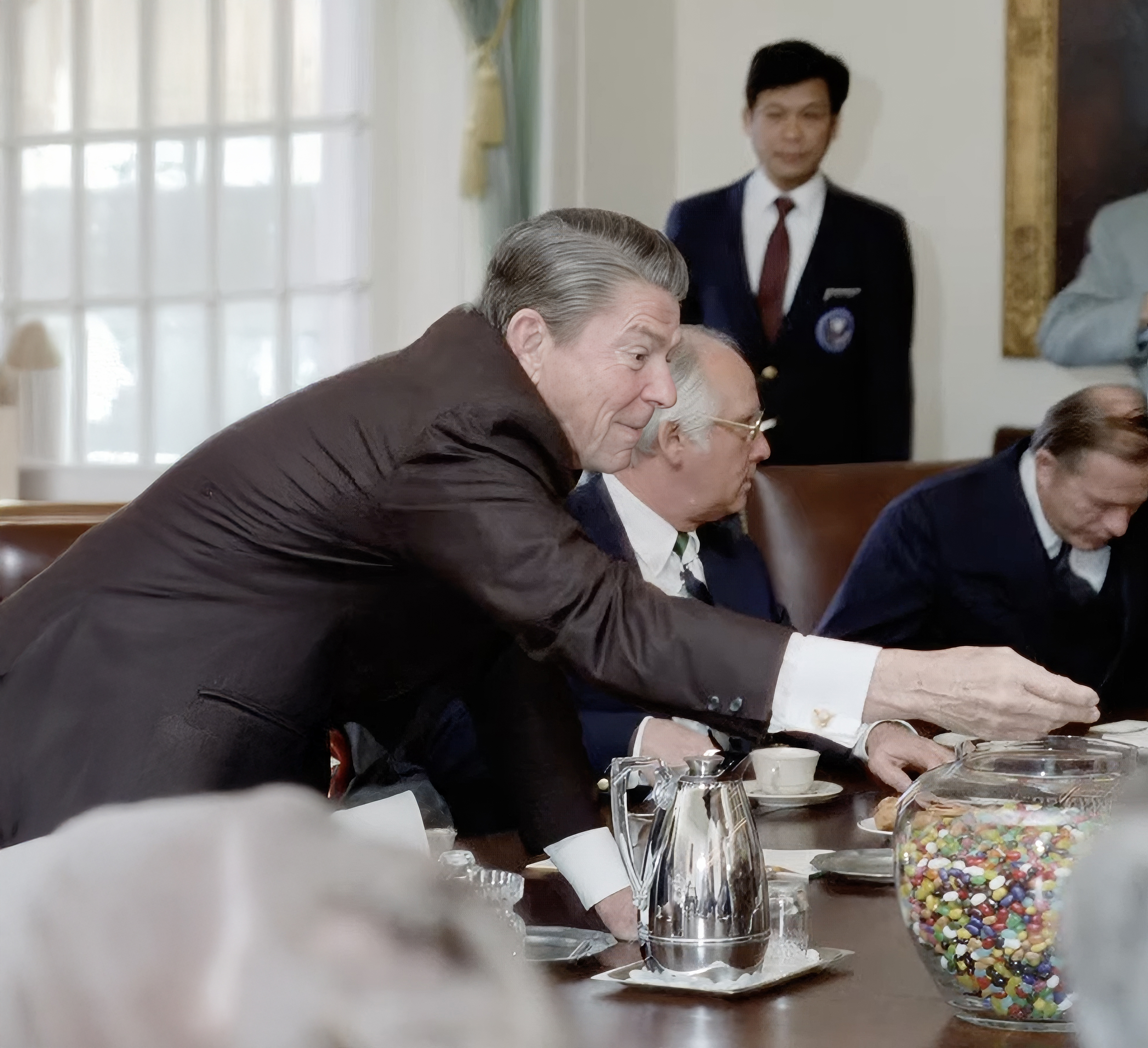Photo of Reagan reaching for a jar of jelly beans at a large brown table