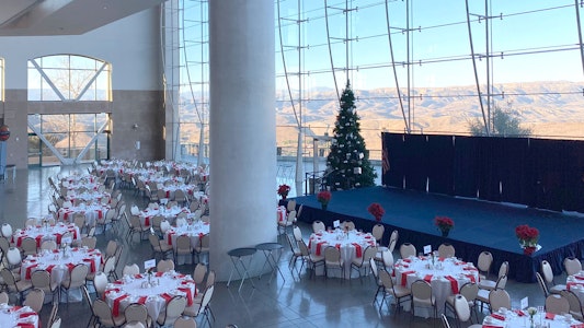 Tables set for a gathering, Christmas tree and stage.