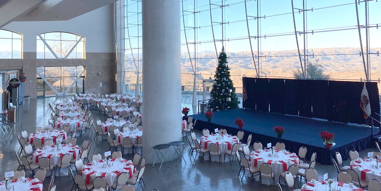 Tables set for a gathering, Christmas tree and stage.