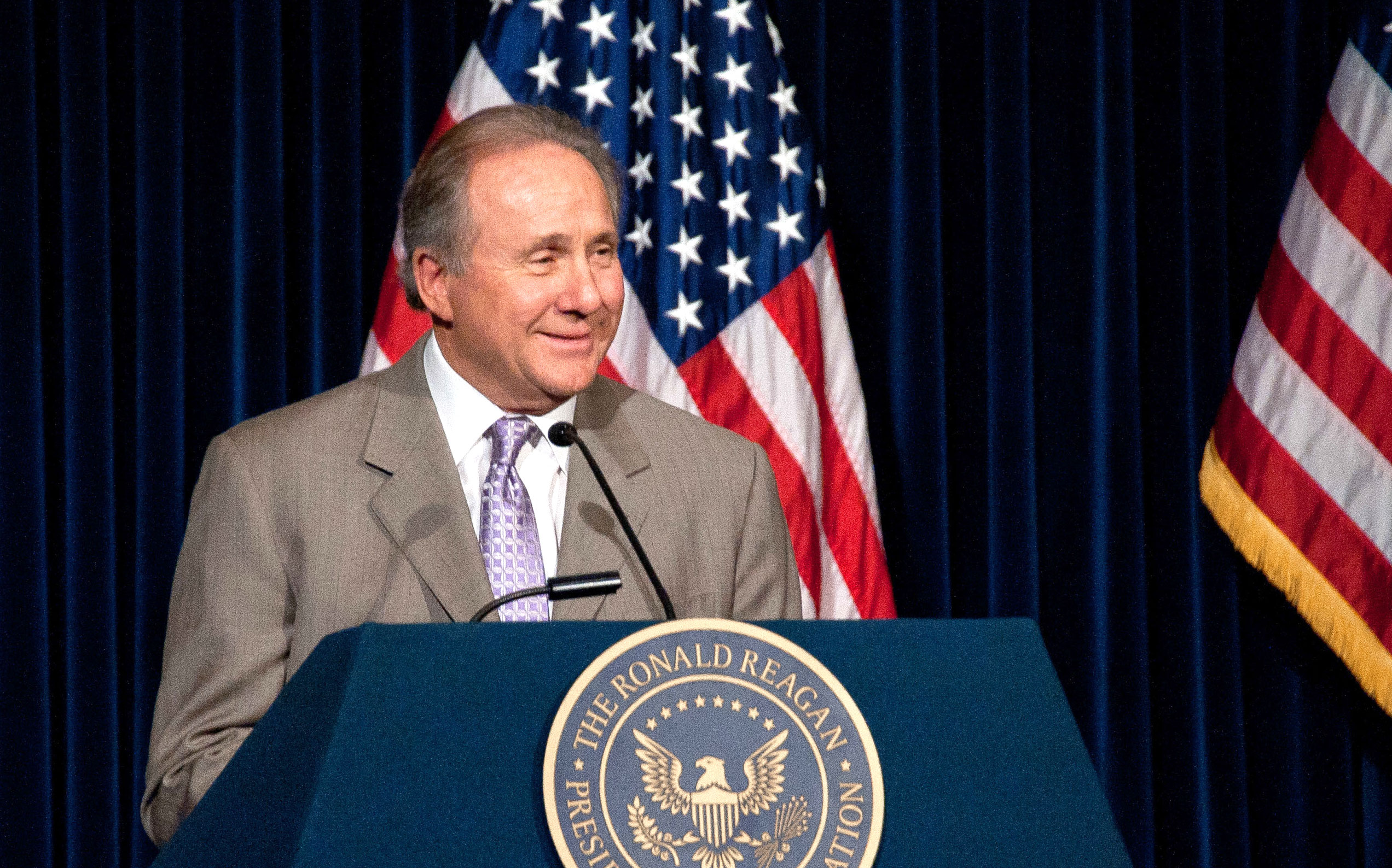 Michael Reagan speaking on podium at the Reagan Library.