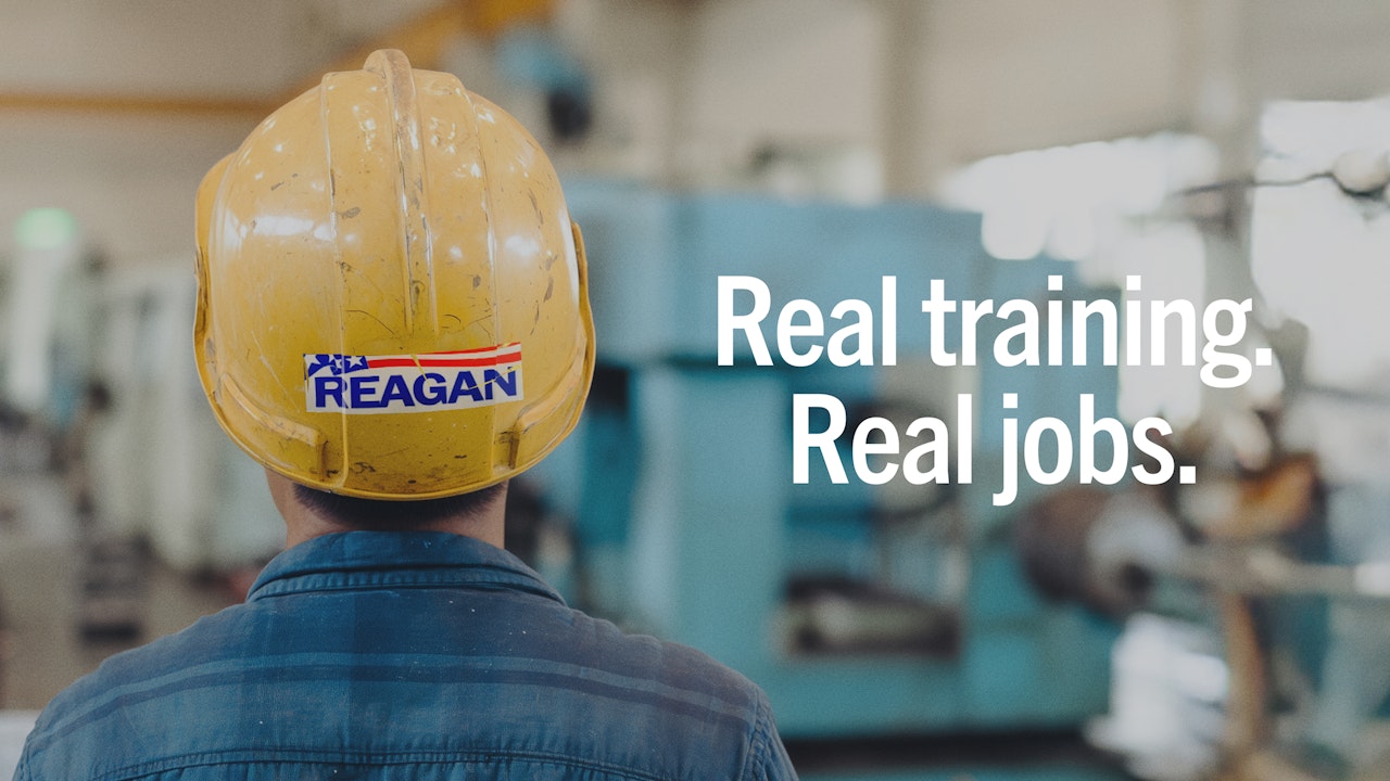 A boy in a yellow safety helmet with a red white and blue Reagan sticker on the back