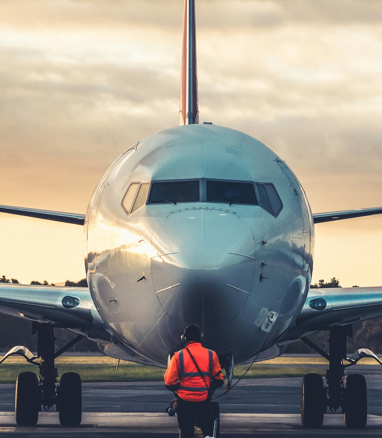 Man standing in front of plane in bright orange jacket