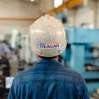 A person looking to michenery wearing a hard hat with a Reagan sticker.