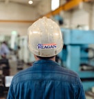 A person looking to michenery wearing a hard hat with a Reagan sticker.