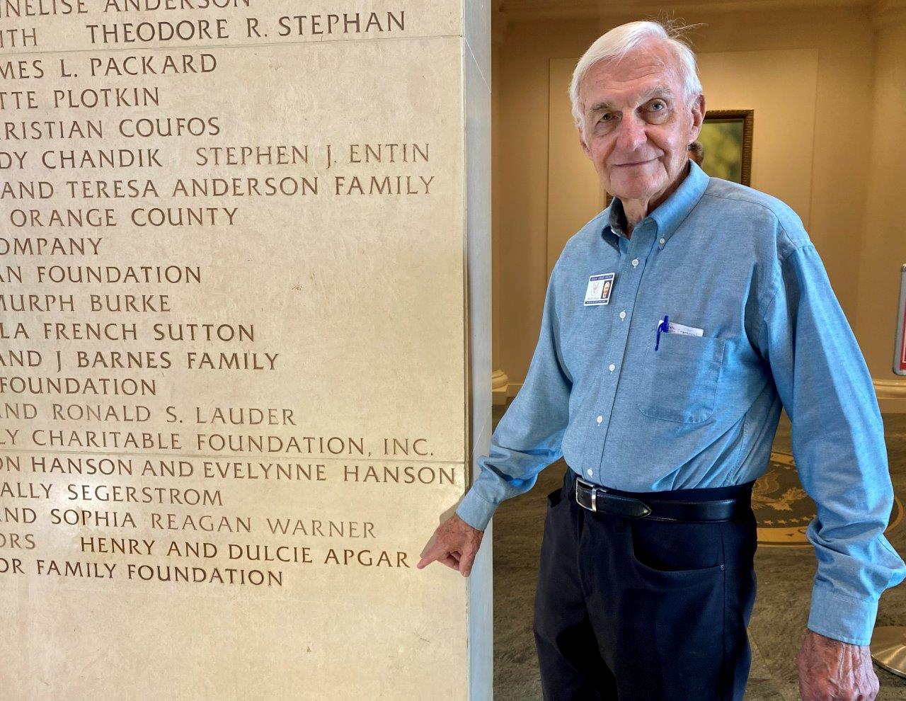Henry Apgar ponting at the donor wall