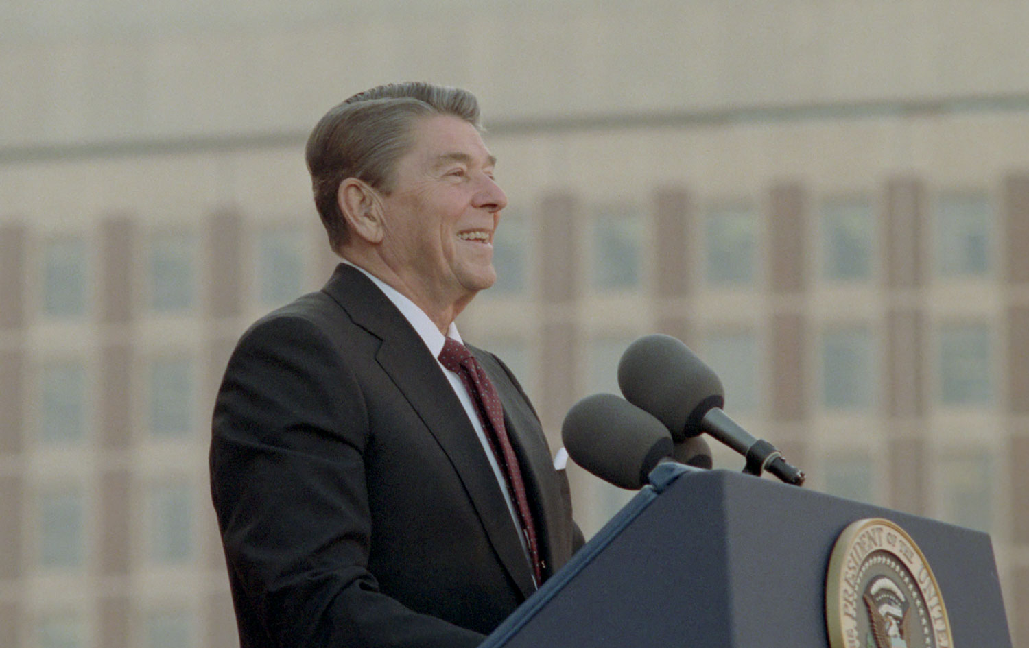 President Reagan standing at the podium during a trip to Boston Massachusetts at a Reagan Bush Rally at the City Hall Plaza